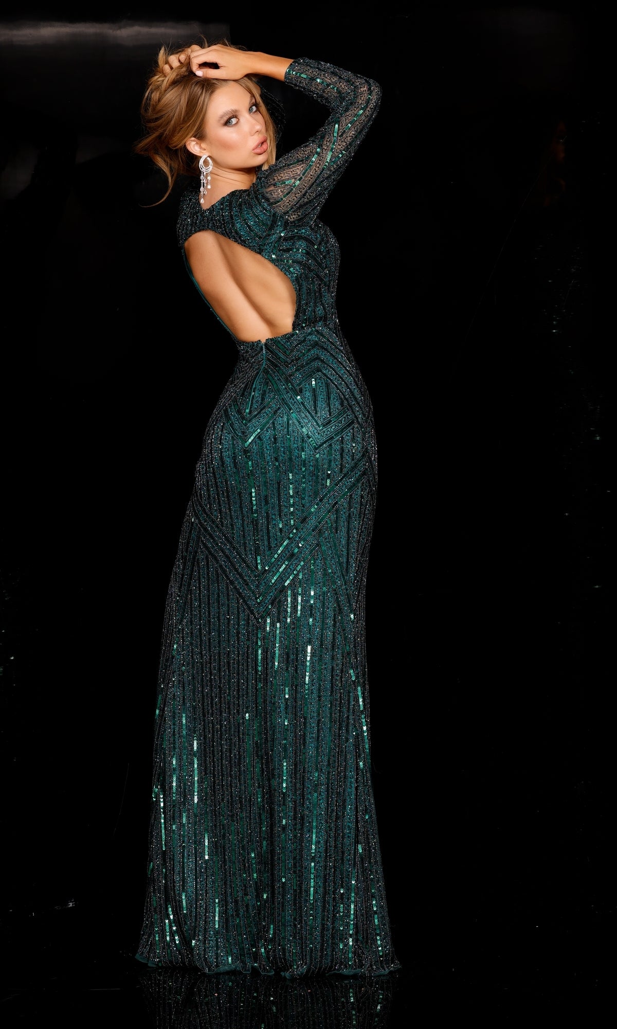 A woman in a dazzling Plunging V-Neck Green Long Sleeve Long Sequin Gown stands against a black background, glancing over her shoulder with one hand resting on her head.